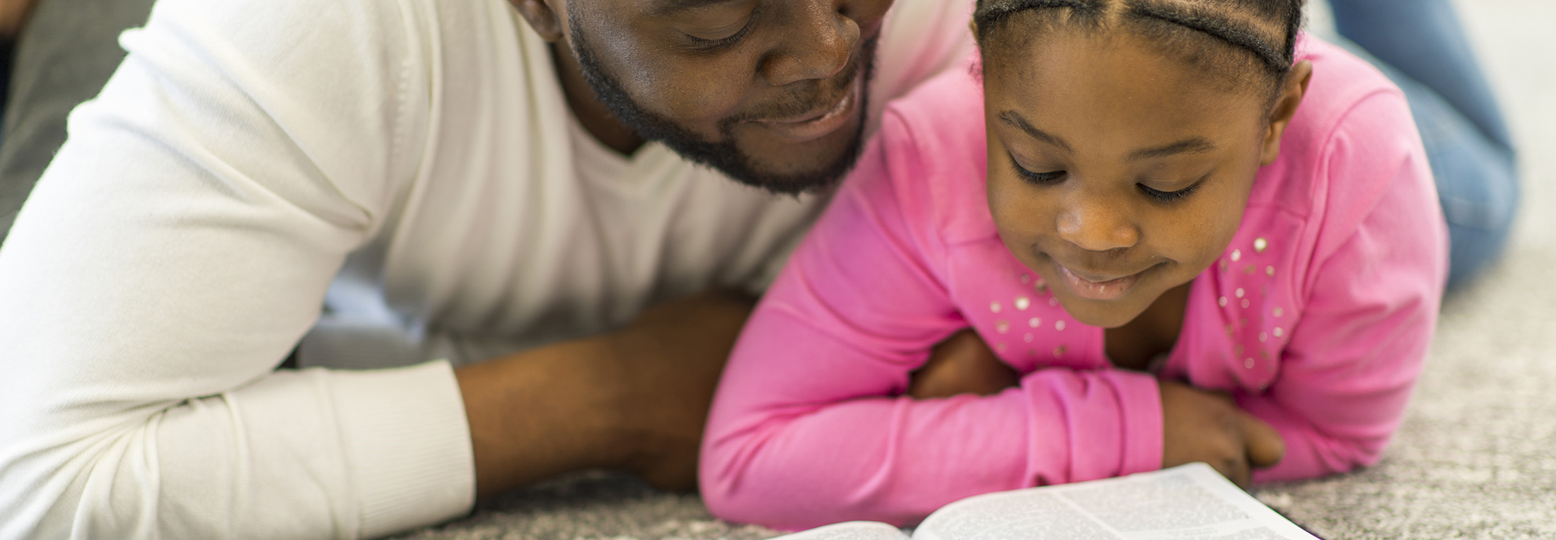 Father and daughter reading a bible story for children together.